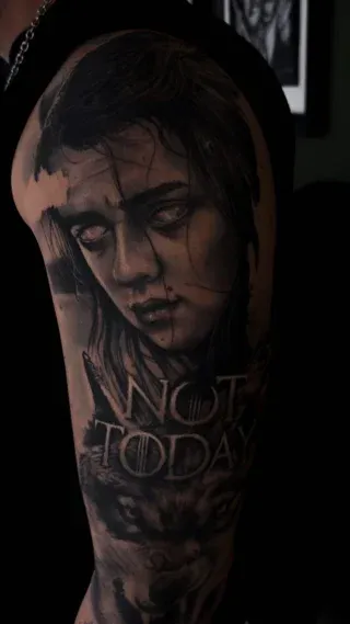 Schattiertes Frauenporträt als Black-and-Grey-Tattoo auf einem Oberarm.