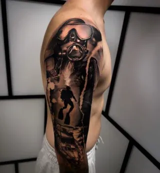 Dunkles Black-and-Grey-Tattoo einer Figur mit Gasmaske und szenischem Hintergrund auf einem Oberarm.